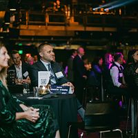 Dim gala room with guests at tables, photographed without flash