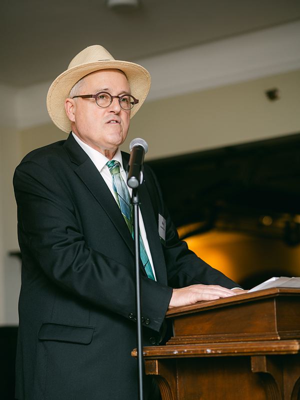 Speaker at a wooden podium with a microphone during an anniversary celebration