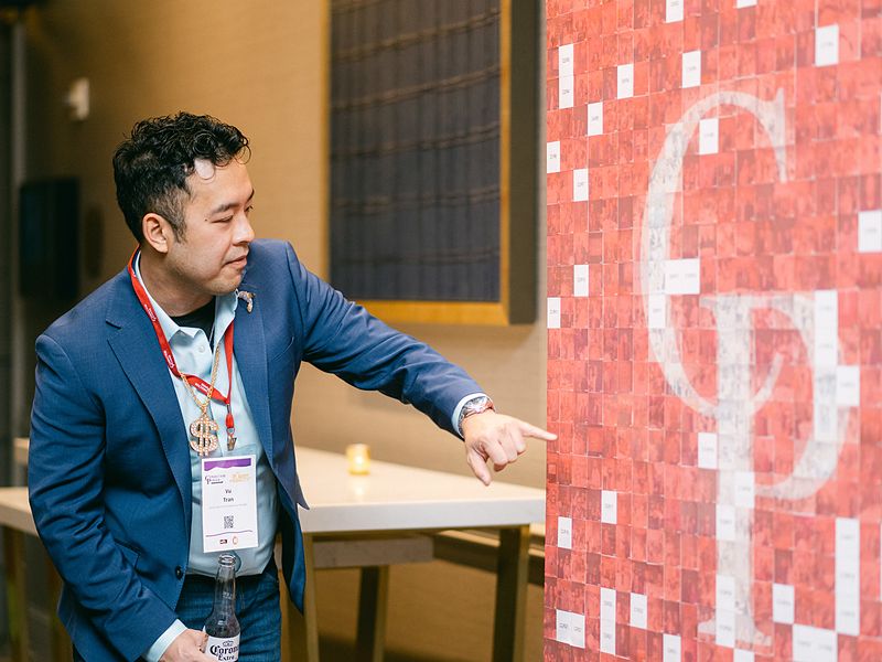 Guest pointing at a photo mosaic logo wall at a brand activation