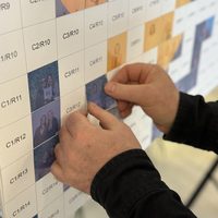 Numbered photo sticker tile being placed on a mosaic board
