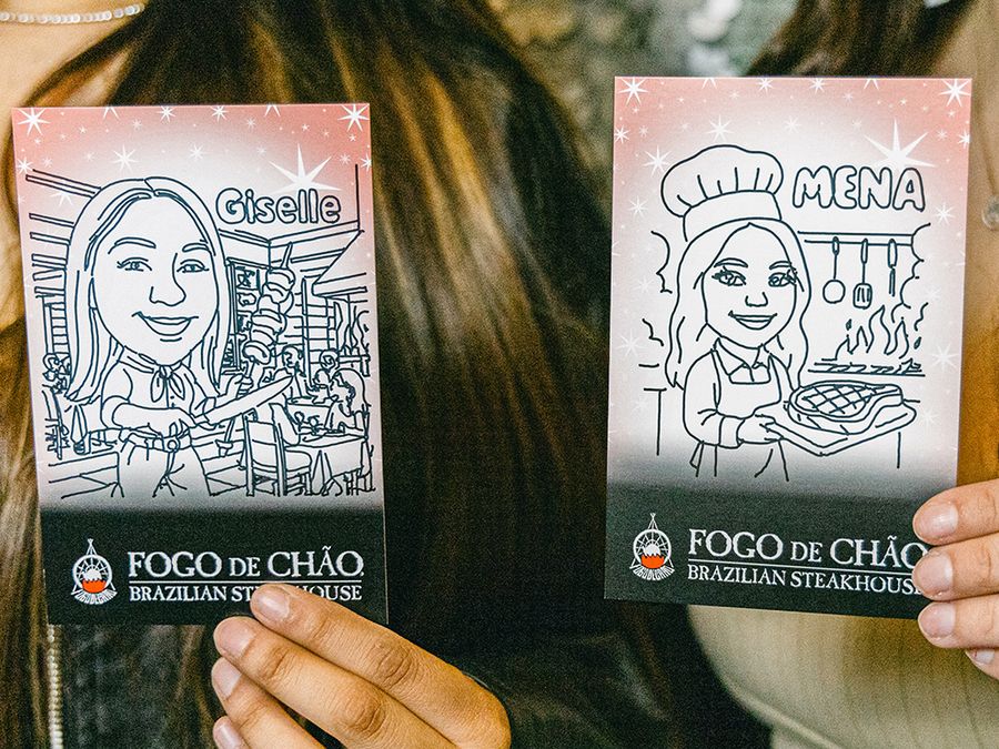 Two guests holding up their robot drawn portrait cards