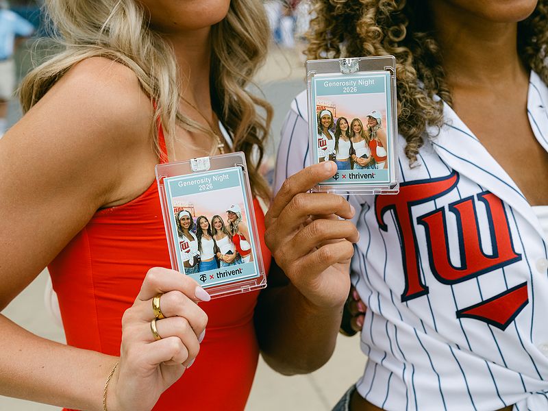 Two guests at a ballpark holding sports cards printed on site at a photo booth activation