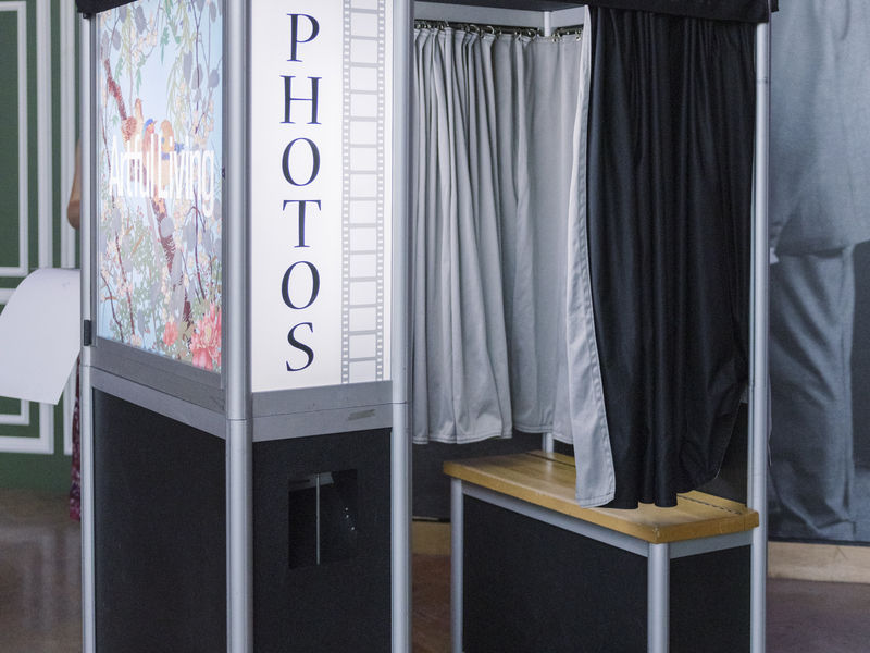 Traditional photo booth with curtain and bench at a museum event