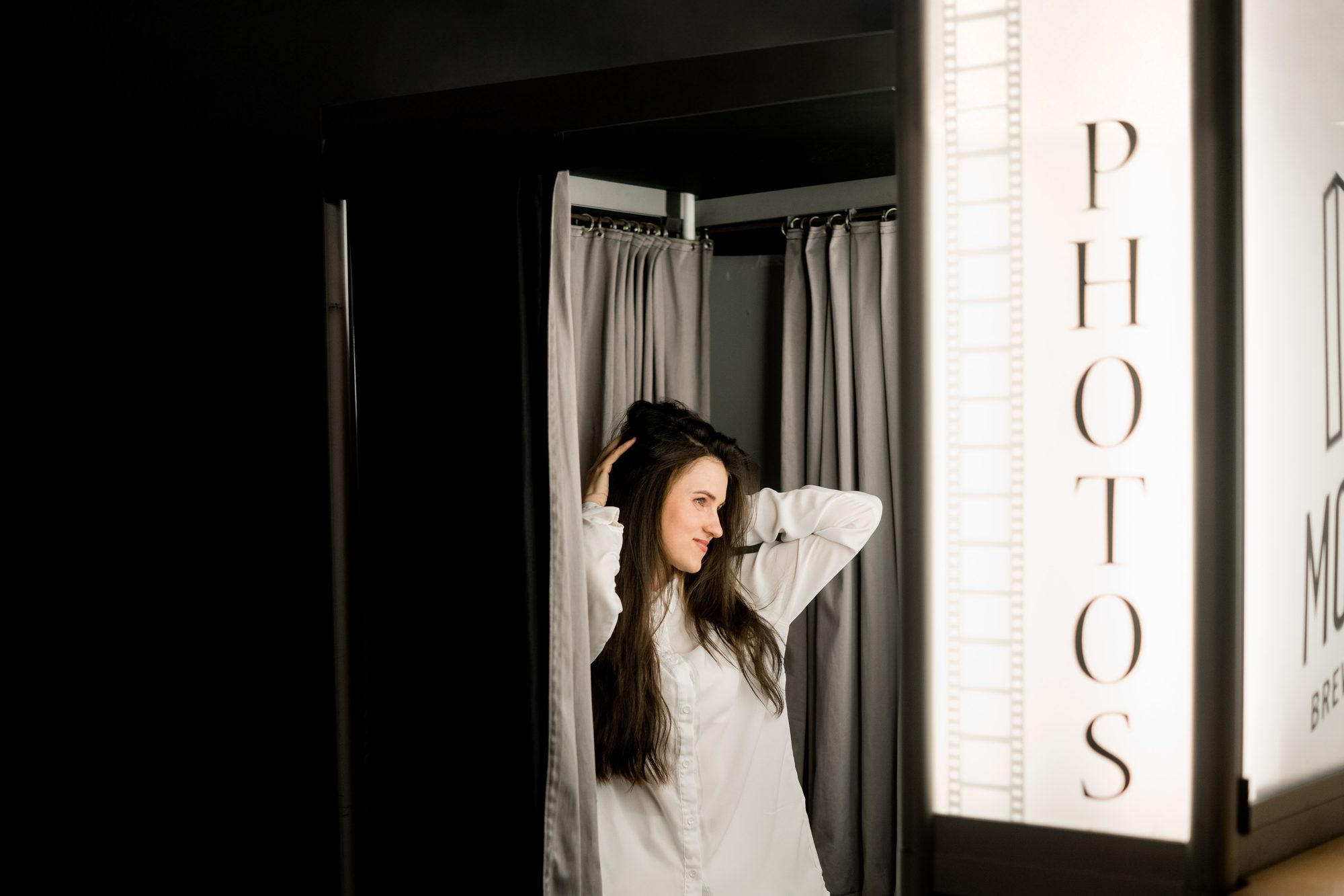 Guest behind the curtain of a traditional enclosed photo booth at a Minneapolis event